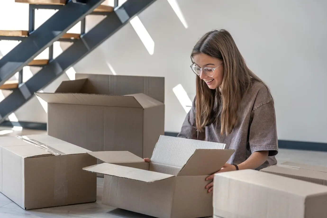 Mädchen mit Kartons, Umzug und Auspackreihenfolge im neuen Zuhause