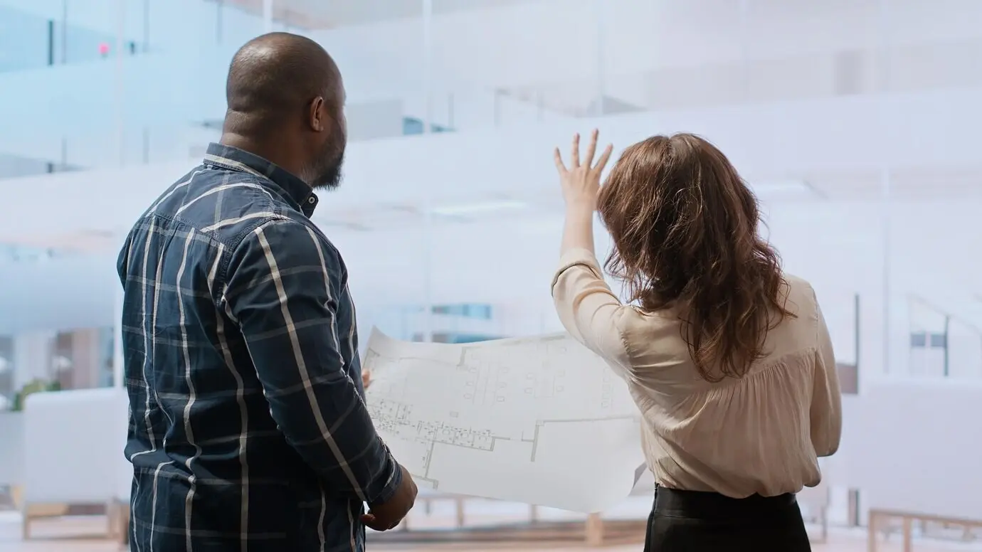 Geschäftsfrau erläutert ihre Vision für die Renovierung auf Plänen.